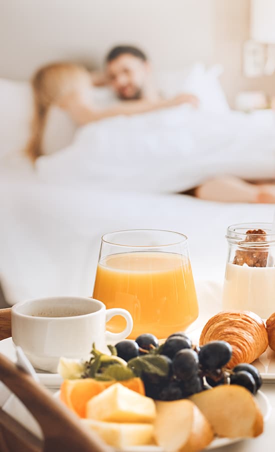 Couple enjoying breakfast in bed room service in their St. Charles, IL accommodations